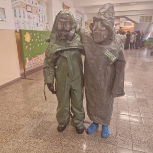 žiaci oblečení v protichemickej ochrane