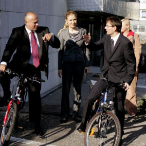 Aj z Detskej fakultnej nemocnice  na Úrad vlády odchádza minister obrany na elektrobicykli. Sprevádza ho ochrankár, v strede riaditeľka Kancelárie ministra obrany Margaréta Cehláriková